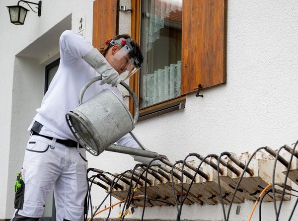 Arbeiter bedient Metallgerät an Außenwand.