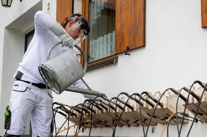 Arbeiter bedient Metallgerät an Außenwand.