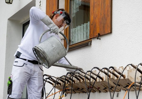 Arbeiter bedient Metallgerät an Außenwand.
