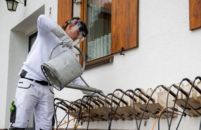 Arbeiter bedient Metallgerät an Außenwand.
