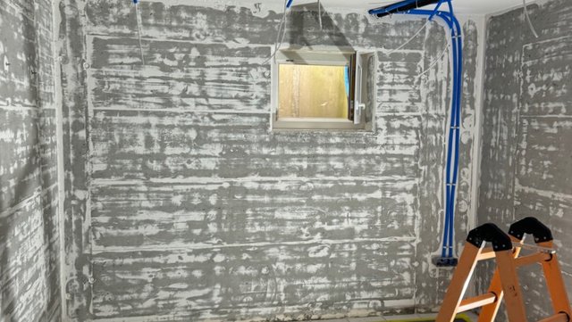 Graue Wandfläche mit horizontalen Spuren in leerem Raum, Fenster mittig
