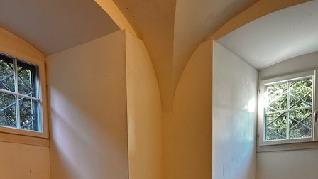 Leerer Raum mit Gewölbebogen und zwei Fenstern