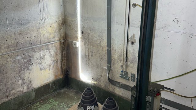 Schimmelbefall an Kellerwand mit Leitungen und Sockelbereich, Eckansicht