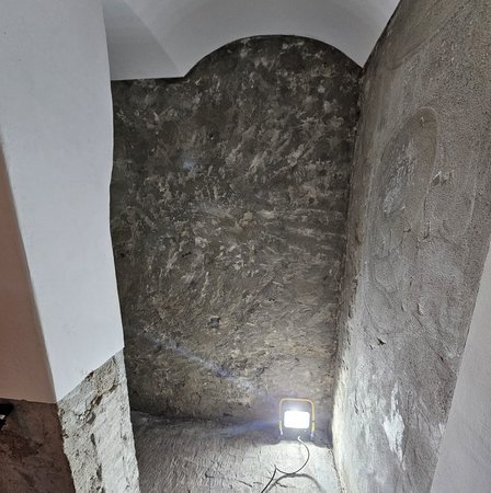 Roh verputzte Nische mit grauer Masse an Wänden, beleuchtet von Baustrahler