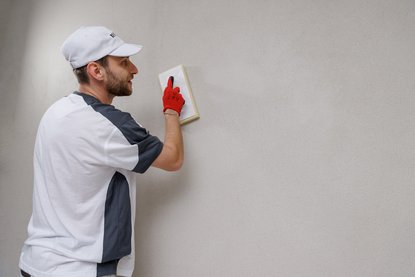 Arbeiter glättet helle Wandfläche mit Reibebrett