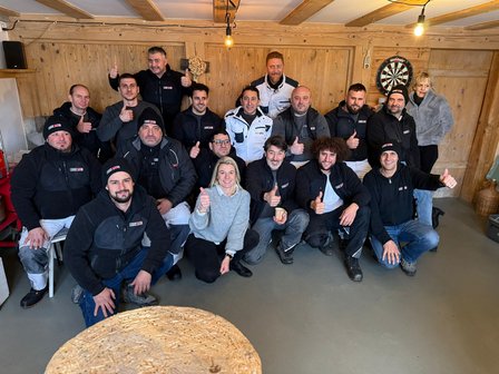 ISOTEC Team posiert in Holzraum mit erhobenem Daumen.