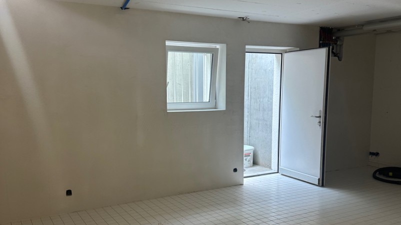 Leerer Kellerraum mit gefliestem Boden, Fenster und offener Tür