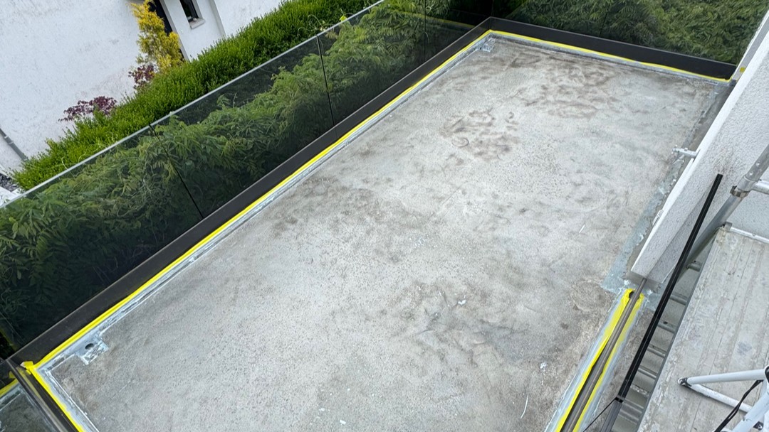 Grauer Balkonboden mit Verfärbungen, umlaufend gelbes Abklebeband an den Rändern