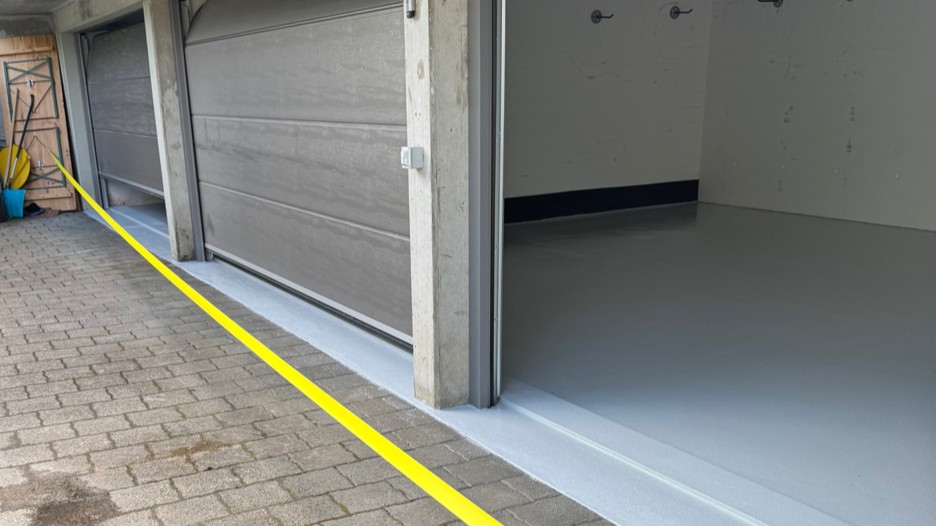 Garageneinfahrt mit geöffnetem Tor und frisch beschichtetem grauem Boden