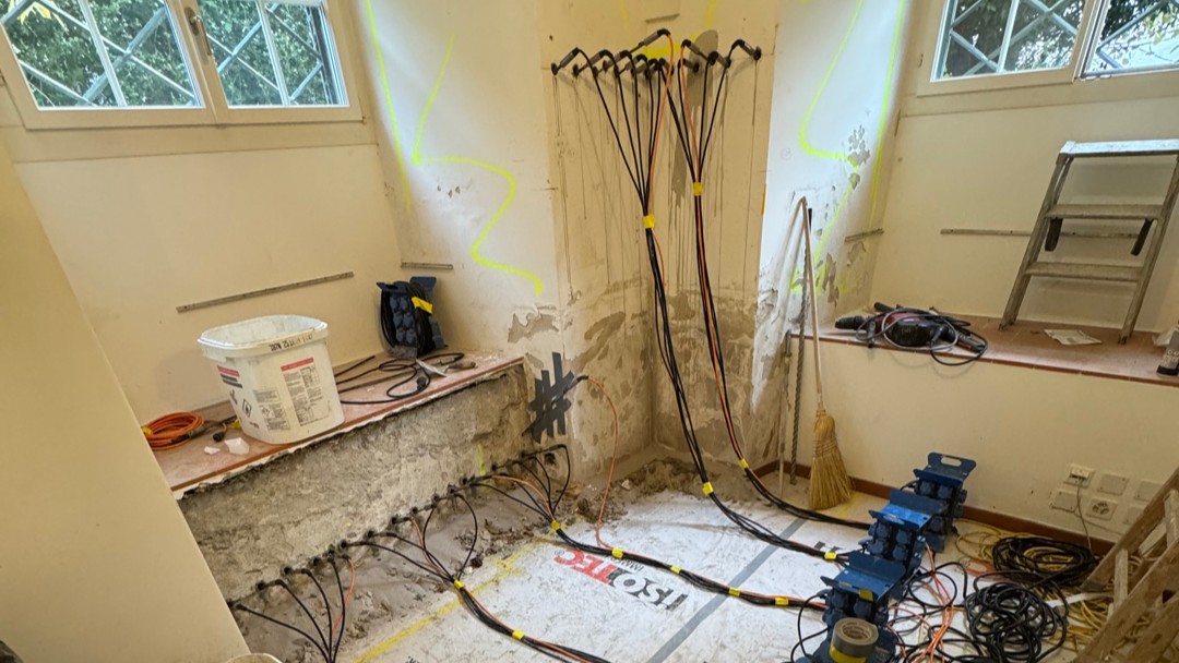 Freigelegte Kellerwand mit Bohrlöchern und schwarzen Schläuchen bei Sanierungsarbeiten