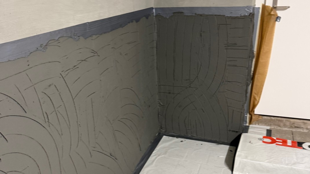 Graue Masse auf Kellerwandecke, Nahaufnahme mit Zahnspachtelrillen