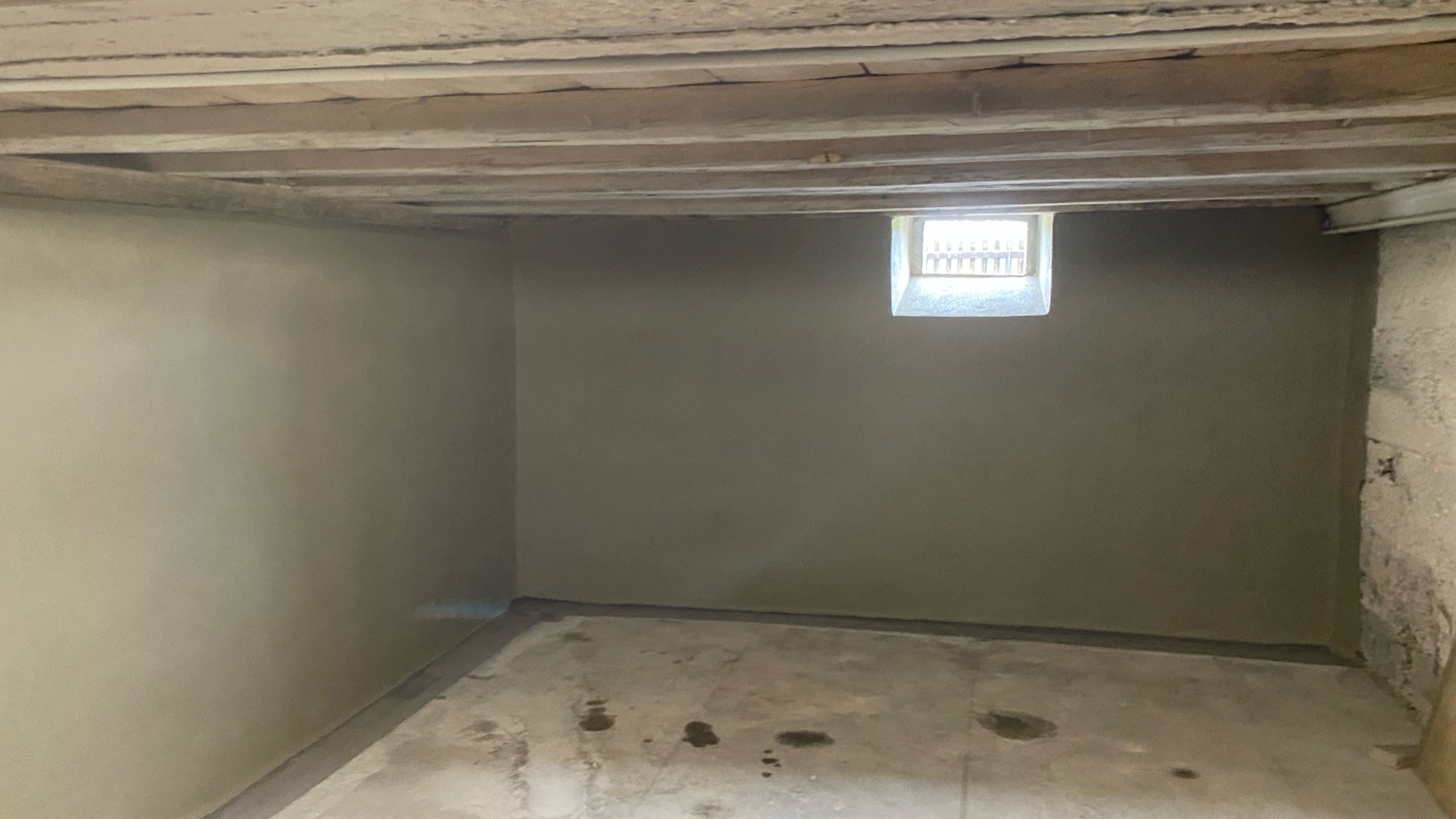 Glatte graue Wände in leerem Kellerraum mit kleinem Fenster