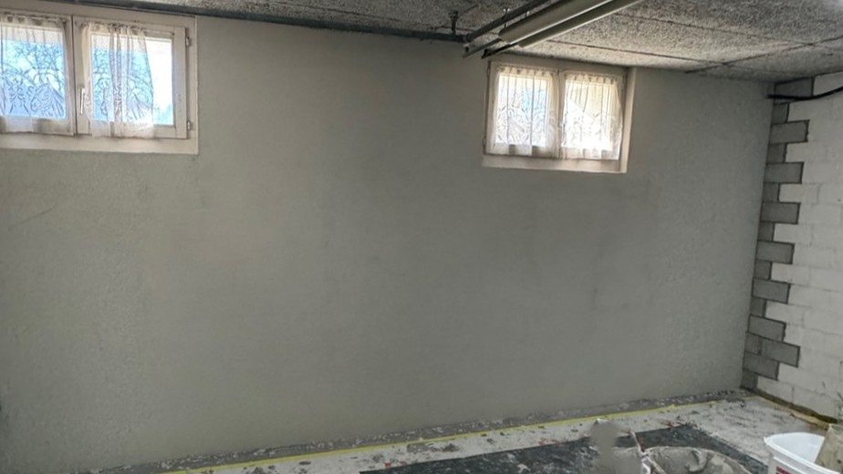 Graue Wand in Kellerraum mit zwei kleinen Fenstern, frisch beschichtet