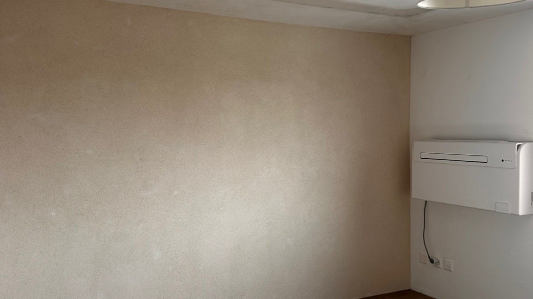 Helle Zimmerwand mit großflächigen Feuchteflecken neben montierter Klimaanlage