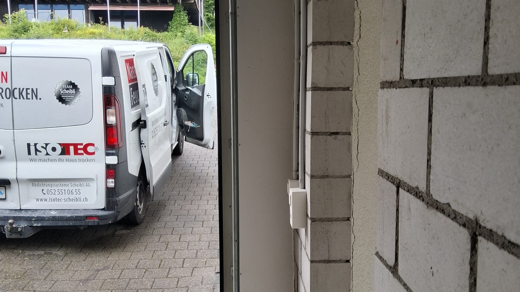 ISOTEC Transporter mit offener Tür neben Riss in heller Kellerwand