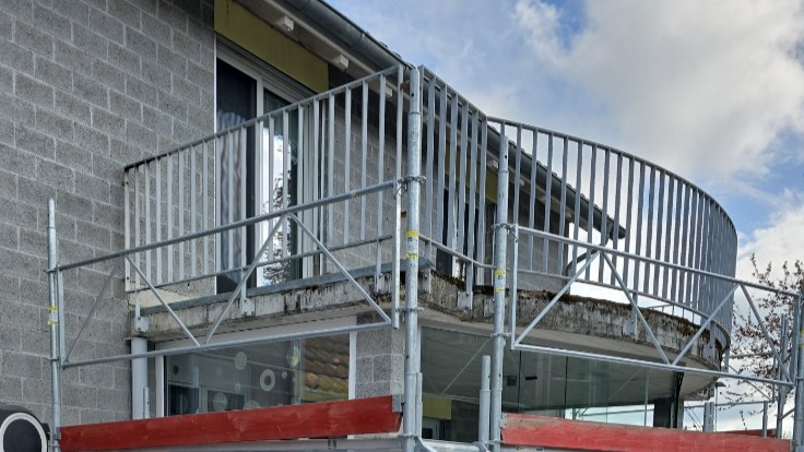 Geruest vor Balkon mit gebogener Metallbruestung an Gebaeudeecke