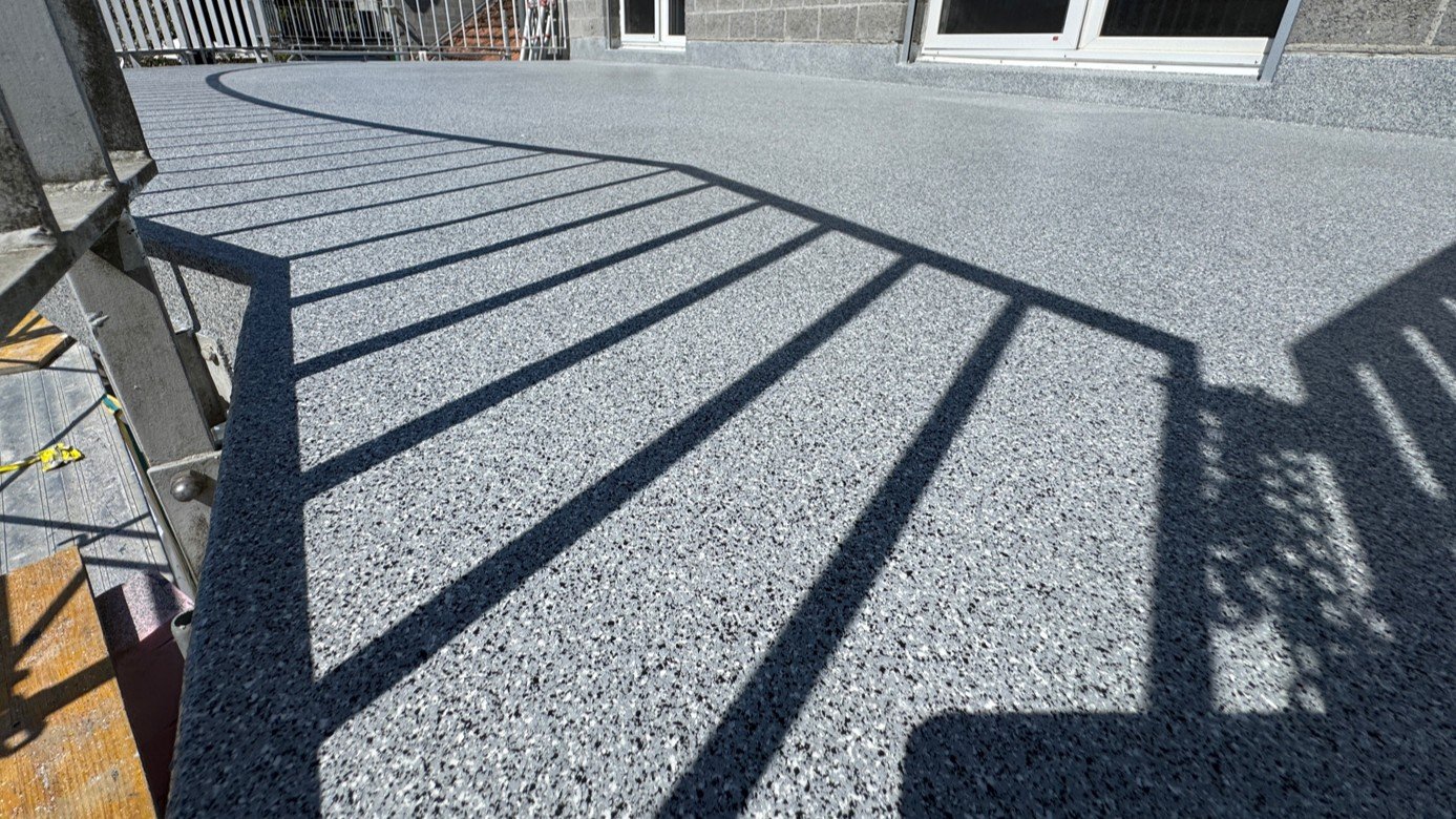 Grauer Balkonboden mit körniger Beschichtung und Geländerschatten