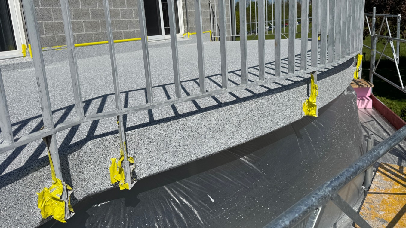 Grauer Balkonbelag mit Metallgeländer, abgesperrte Pfosten im Gerüst