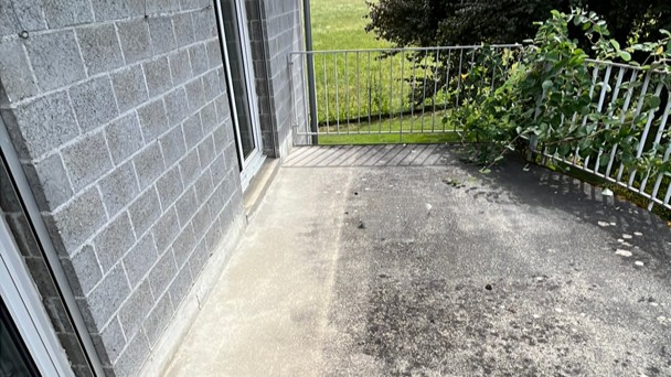 Balkonboden mit dunklen Flecken und Betonwand, Außenansicht