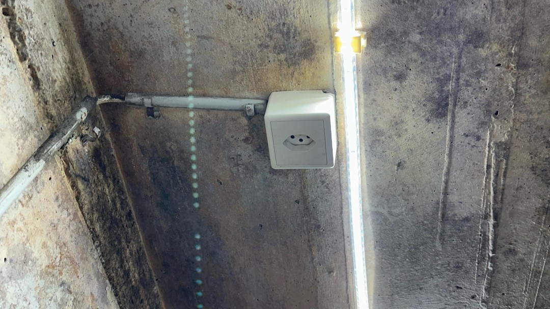 Dunkle Flecken an Kellerdecke mit Steckdose, Kabelkanal und Leuchtstoffröhre.