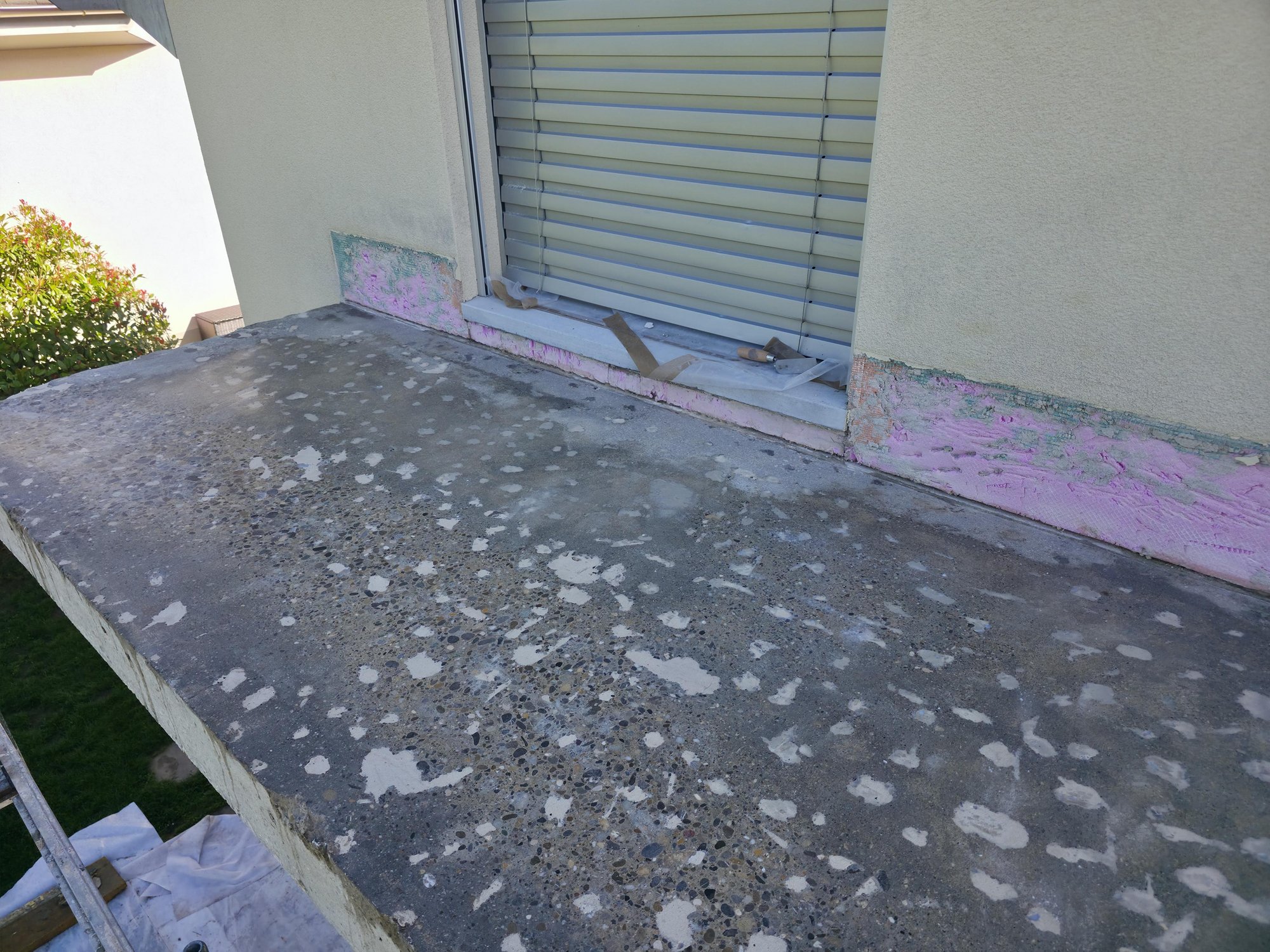 Betonbalkon vor Fenstertuer, Sockelbereich mit pinker Masse freigelegt und Abdeckfolie