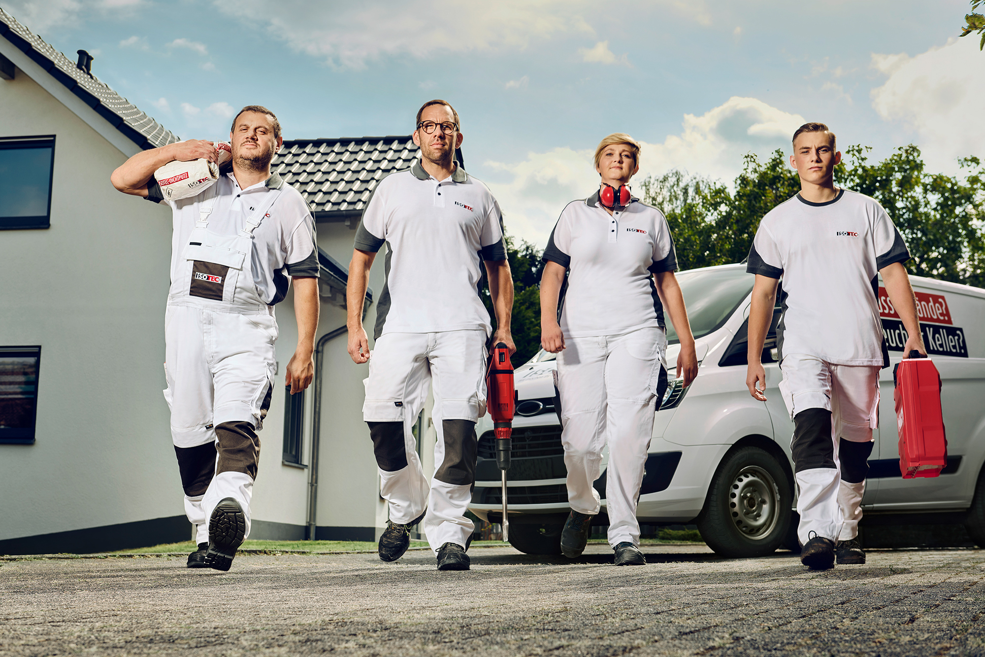 ISOTEC Team läuft mit Werkzeug vor einem Haus entlang.